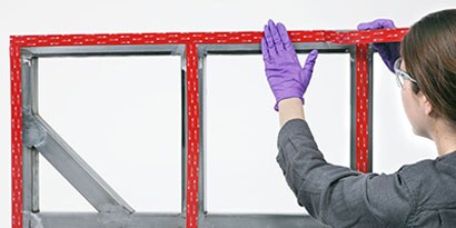 Person attaching vhb tape to frame for subsequent attachment to panel
