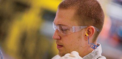 Worker wearing 3M earplugs and protective eyewear
