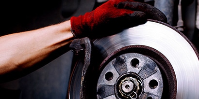 Mano con guante 3M tocando componente metálico automotriz
