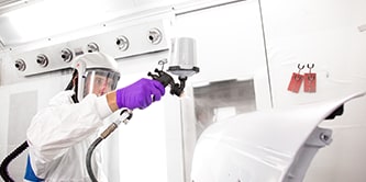 Técnico aplicando primer en coche para pintarlo.
