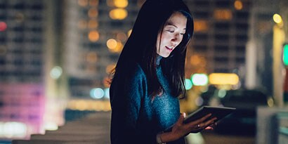 Mujer en oficina usando una tablet con vista a la ciudad
