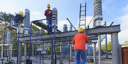 Hombres con cascos protectores que trabajan en una subestación eléctrica
