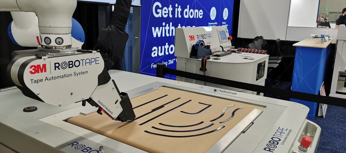 Image of two yellow robot arms, each with a RoboTape application head attached