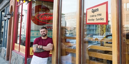 Un propietario de restaurante parado afuera de su restaurante.
