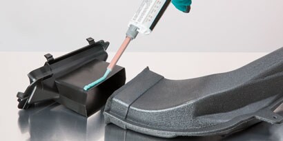 Applying a bead of a two-part structural adhesive onto a tube for insertion into a larger rectangular tube.
