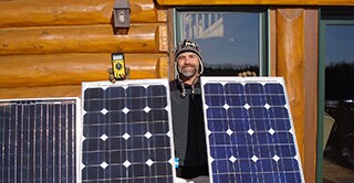 3M scientist Tim Hebrink holding the solar panels that have helped him generate about 80 percent of his home&rsquo;s energy.