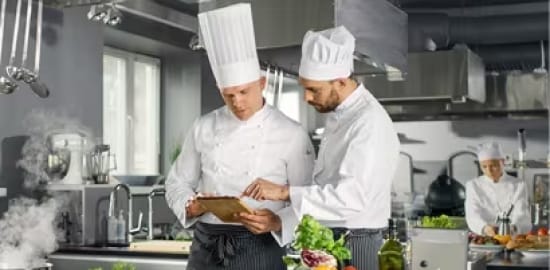 Dos cocineros trabajando en una cocina comercial.
