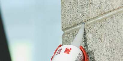 Sealant being applied to seams of concrete wall exterior
