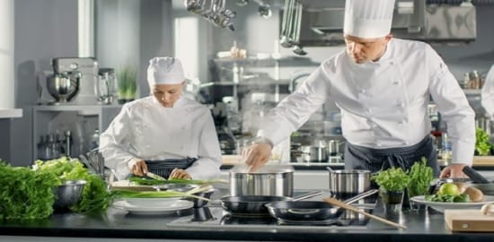 Dos cocineros trabajando en una cocina comercial.
