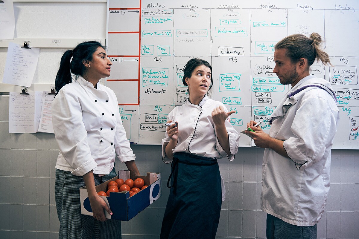 Tres cocineros de un restaurante organizando sus horarios de trabajo.
