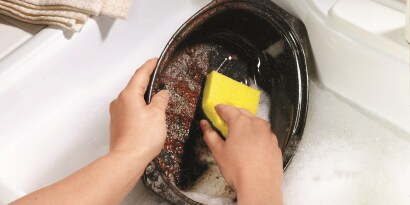 Una persona lavando un plato con una fibra-esponja de 3M.