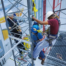 Several workers climbing a structure wearing 3M Fall Protection during a training session