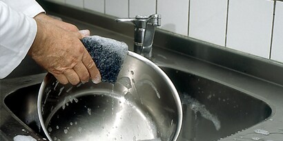 Una persona lavando una olla.