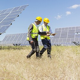 Dos hombres caminan junto a paneles solares que producen energía solar