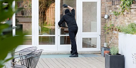 Una persona intentando entrar en una casa por la ventana.
