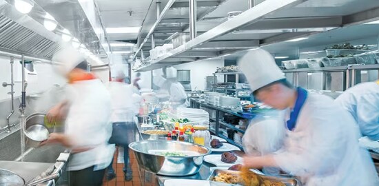 Un grupo de chefs trabajando en una cocina comercial.
