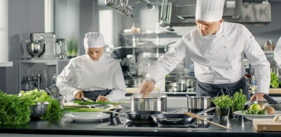 Dos cocineros trabajando en una cocina comercial.

