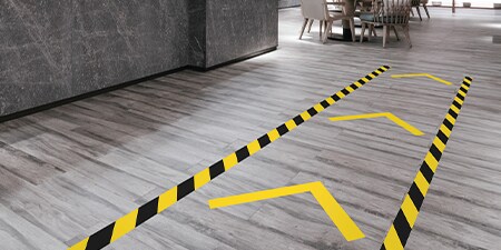Primer plano de cintas 3M de señalización de pisos aplicadas en forma de flecha.
