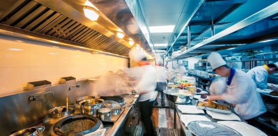 Varios chefs trabajando en una cocina comercial moderna.
