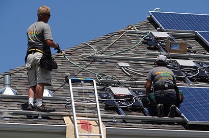 Maureen Tholen and husband putting solar panels on the roof of their home.