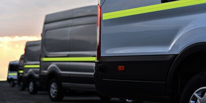 Line of parked vans with highly visible, reflective conspicuity tape.
