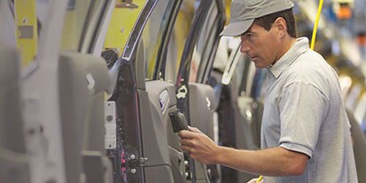 Imagen de fabricante trabajando sobre la puerta de un automovil
