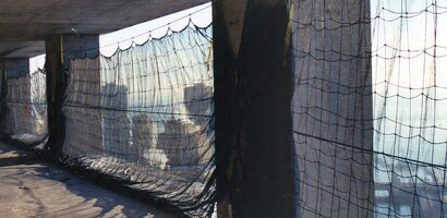 Image of vertical nets blocking open exterior walls of tall building under construction
