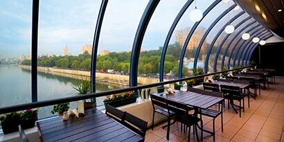 Un restaurante con grandes ventanas curvas mira hacia un cuerpo de agua.
