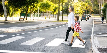 Woman and child confidently crossing the street at mid-block crossing with curb bump out and painted lines.
