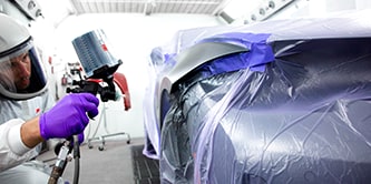 Técnico pintando un coche.
